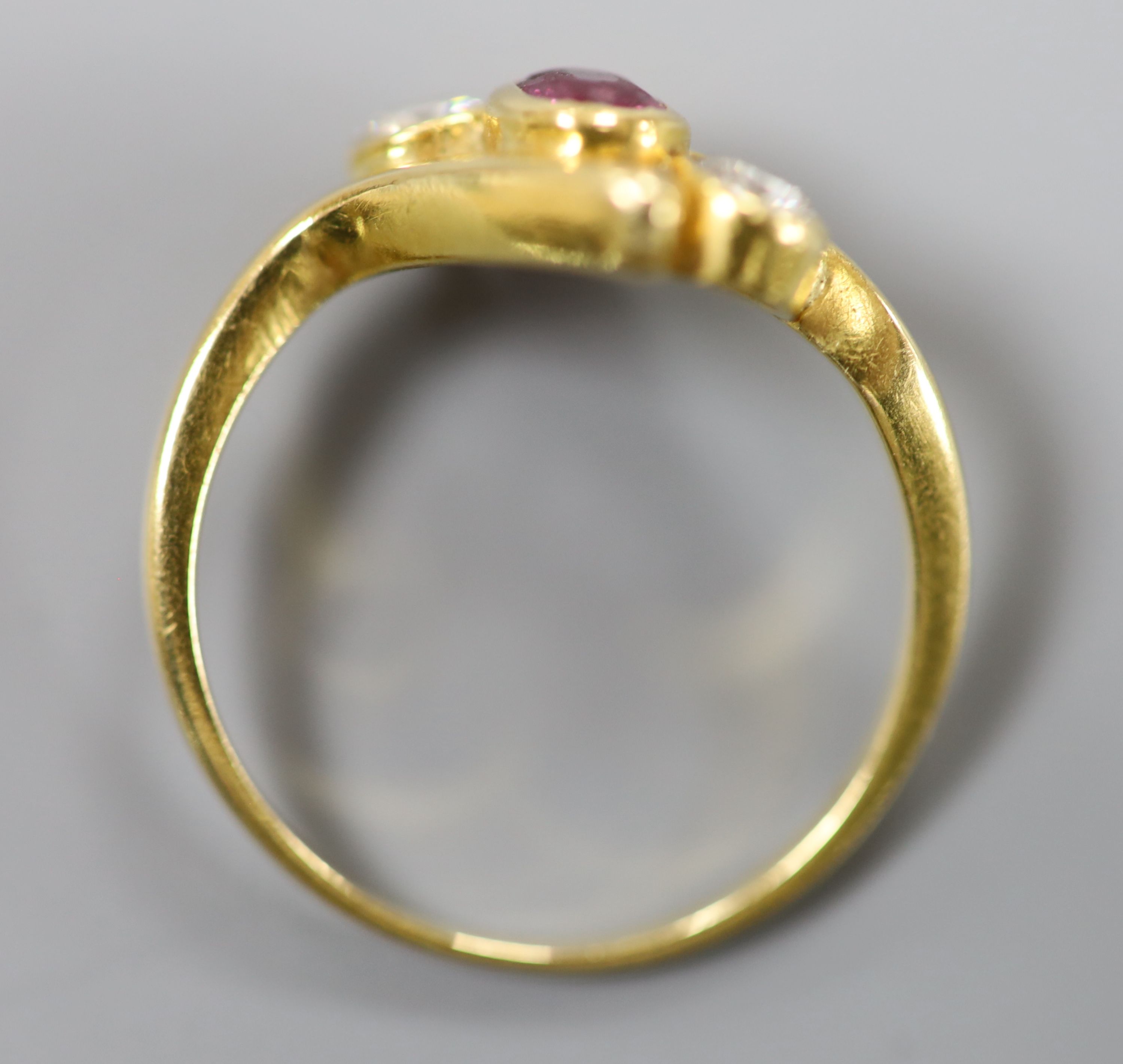 A 750 yellow metal, ruby and diamond three stone crossover ring, size P, gross 4 grams.